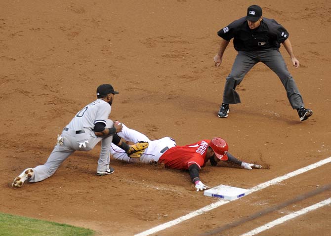 Chicago White Sox shortstop Alexei Ramirez, left, tags out Texas Rangers' Elvis Andrus, center, after a rundown in the first inning of a baseball game on Saturday, April 19, 2014, in Arlington, Texas. Umpire James Hoye watches the play. (AP Photo/Matt Strasen)