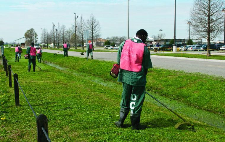 Inmates cut the grass in the shadow of Alex Box Stadium before the season's opening game last week.