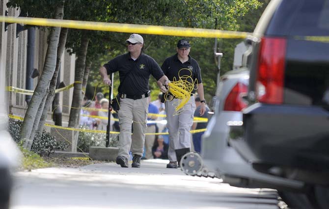 Law enforcement officials roll out dentonater cable Monday, April 7, 2014 near the suspicious package by Thomas Boyd Hall.