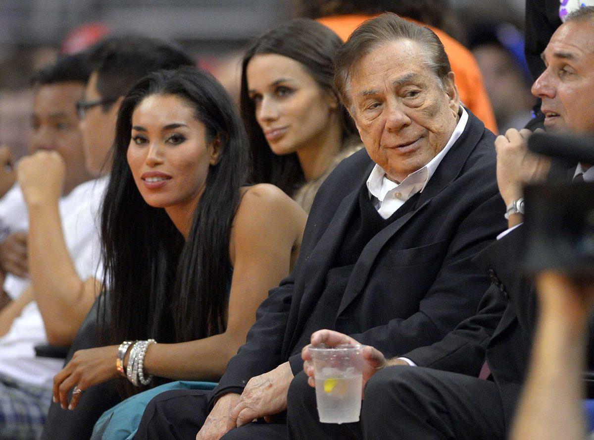 FILE - In this file photo taken on Friday, Oct. 25, 2013, Los Angeles Clippers owner Donald Sterling, right, and V. Stiviano, left, watch the Clippers play the Sacramento Kings during the first half of an NBA basketball game in Los Angeles. Used car dealership chain CarMax says it is ending its sponsorship of the Clippers in the wake of racist comments attributed to Sterling. (AP Photo/Mark J. Terrill, File)