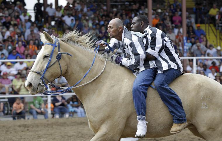 Inmates ride a horse in the Buddy Pick-Up event at the Angola Prison Rodeo in Angola, La., Saturday, April 26, 2014. Louisiana's most violent criminals, many serving life sentences for murder, are the stars of the nation's longest-running prison rodeo. In a half-century, the event has grown from a small event for prisoners into a big business that draws thousands of spectators. (AP Photo/Gerald Herbert)