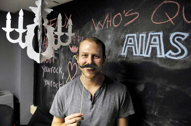 Andrew Pharis, President of the LSU chapter of the American Institution of Architecture Students, shows off the mustache inspired invitations to this year's Beaux Arts Ball April 10, 2013 in Atkinson Hall.