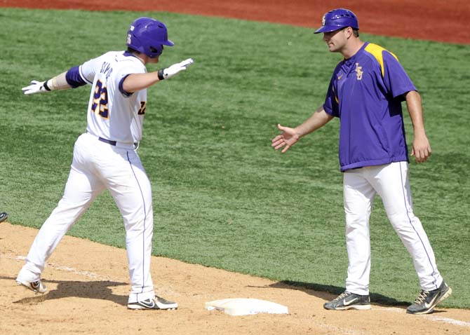 LSU junior catcher Kade Scivicque (22) celebrates with undergraduate assistant coach Alex Edward after making it to first base Friday, May 30, 2014 during the Tigers' 8-4 victory against Southeastern Louisiana in Alex Box Stadium.