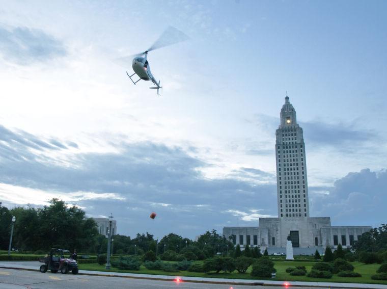 A helicopter drops a package to the ground as part of a theatrical display Saturday, June 28, 2014 before the post-apocalypse themed 5k race "Escape from Baton Rouge" near the Capitol building downtown.