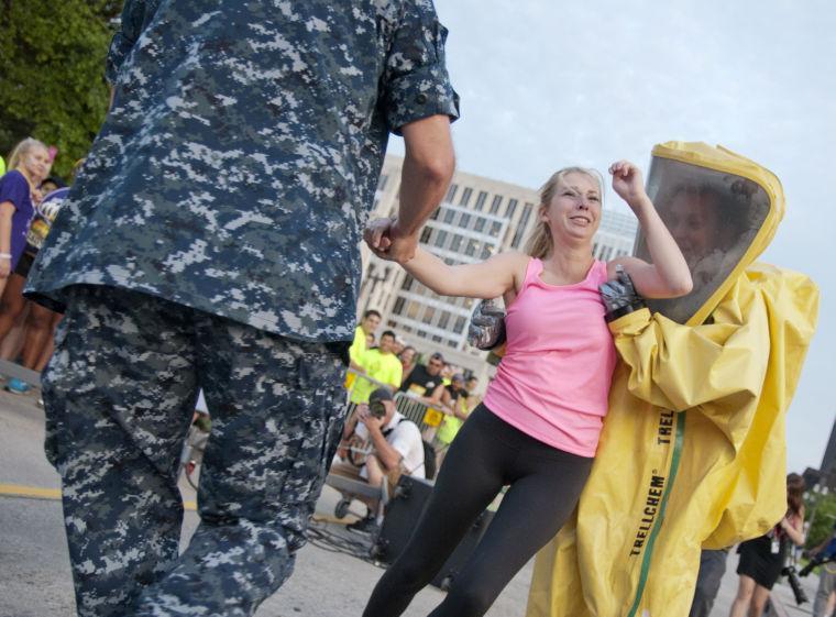 Actors attempt to intimidate race participants by forcibly removing a woman from the starting line and dragging her to a van Saturday, June 28, 2014 before the post-apocalypse themed 5k race "Escape from Baton Rouge" near the Capitol building downtown.