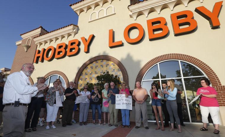 Rev. Bruce Prescott, left, applauds during a vigil outside a Hobby Lobby store in Edmond, Okla., Monday, June 30, 2014, in reaction to the Supreme Court's decision that some companies like the Oklahoma-based Hobby Lobby chain of arts-and-craft stores can avoid the contraceptives requirement in President Barack Obama's health care overhaul, if they have religious objections. (AP Photo/Sue Ogrocki)