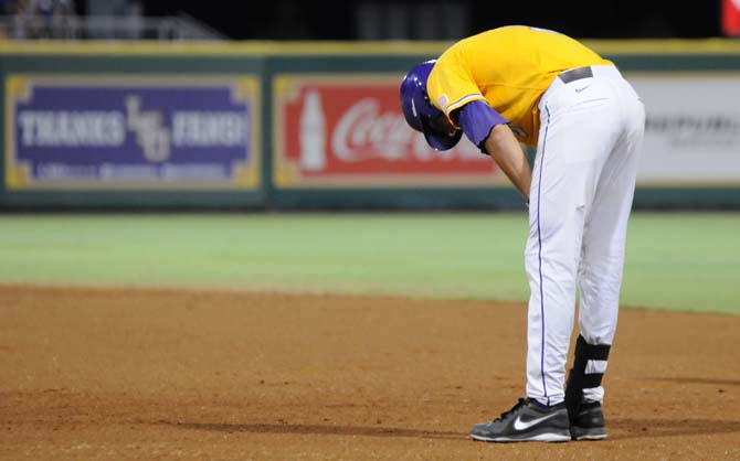 LSU sophomore outfielder Mark Laird (9) bends over to remove his gloves after a fruitless inning Monday, June 2, 2014 during the Tigers' 12-2 loss to Houston in Alex Box Stadium.