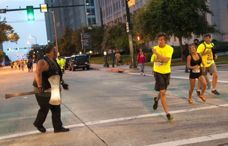 An actor attempts to intimidate race participants Saturday, June 28, 2014 during the post-apocalypse themed 5k race "Escape from Baton Rouge" near the Capitol building downtown.