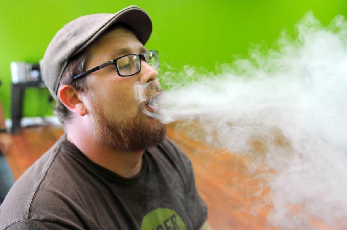 Cameron Kelley, manager of the Baton Rouge Smokecignals, exhales electronic cigarette vapor.