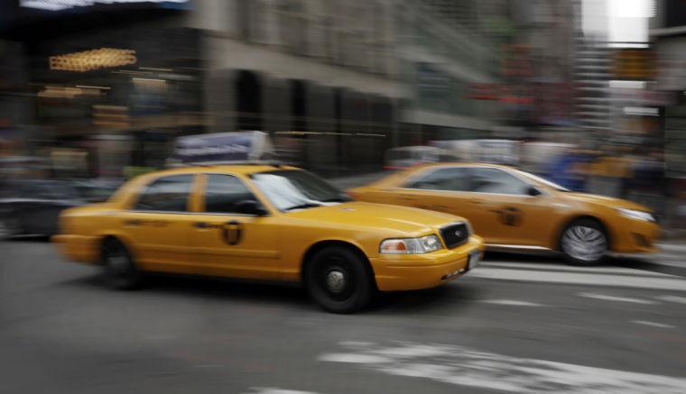 FILE - In this Thursday, Feb. 27, 2014 file photo, New York City taxis drive through New York's Times Square. The car-hailing service Uber is taking on New York City's taxis, temporarily dropping some of its prices by 20 percent starting Monday, July 7, 2014. (AP Photo/Richard Drew)