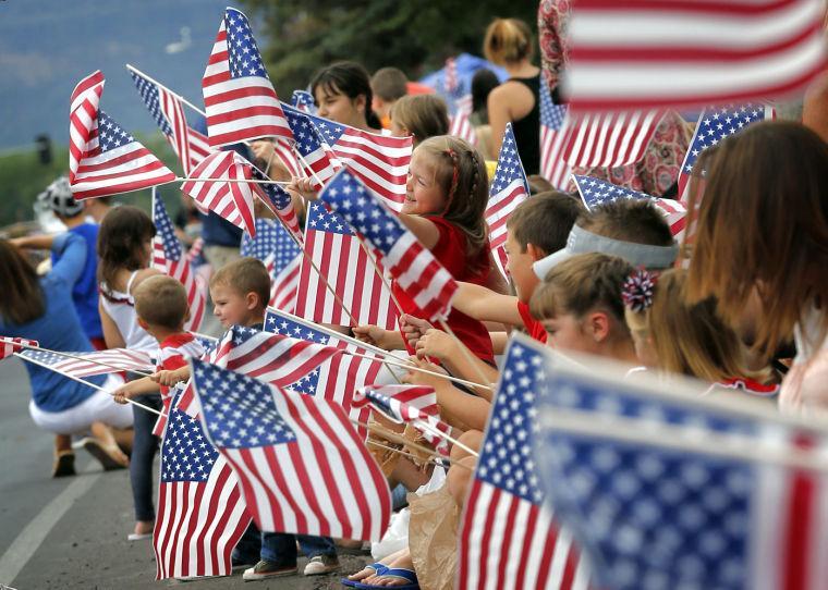 People wave flags as the Independence Day parade rolls down Main Street, Friday, July 4, 2014, in Eagar, Ariz. The Northern Arizona town celebrates the Fourth of July annually with a parade and fireworks. (AP Photo/Matt York)