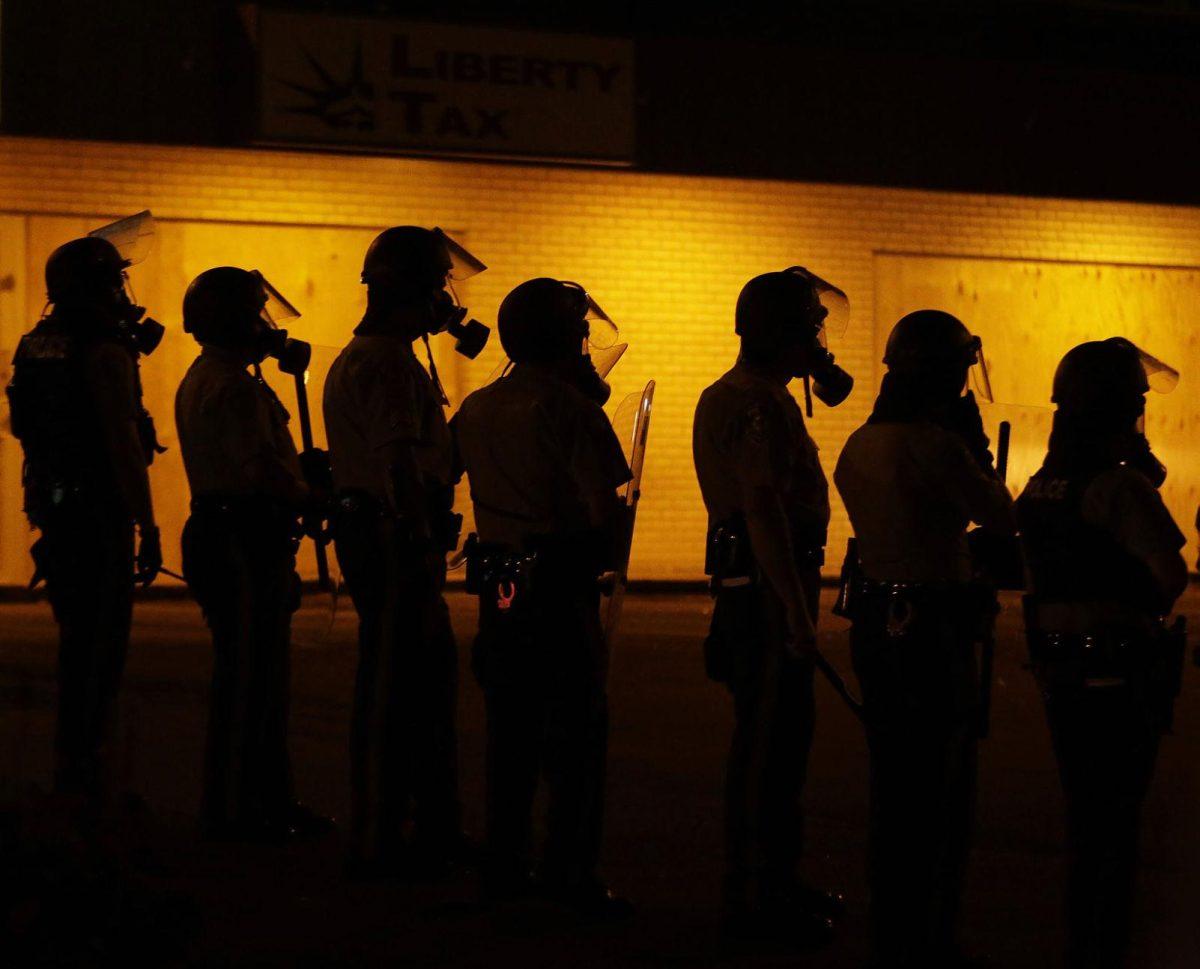 FILE - In this Aug. 17, 2014 file photo, police wait to advance after tear gas was used to disperse a crowd during a protest for Michael Brown, who was killed by a police officer in Ferguson, Mo. Since the shooting, many residents have been afraid to leave their homes at night as protesters clash with police in sometimes violent confrontations. (AP Photo/Charlie Riedel, File)