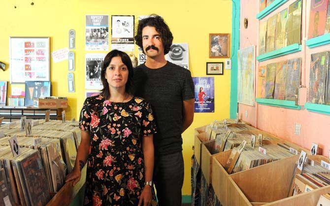 Owners Tess Brunet (left) and Patrick Hodgkins (right) stand with Lagniappe Records mascot Agnes in the new store location at 705 St. Joseph Street.