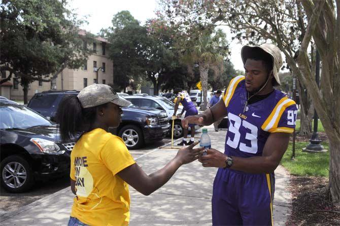 LSU fresman defensive end M.J. Patterson helps student open a water bottle Wednesday, August 20, 2014 during move-in day outside West Hall