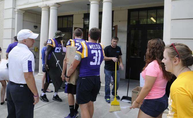 LSU senior defensive end Jermauria Rasco (59), junior punter Jamie Keehn (38) and senior linebacker D.J. Welter (31) assist students move into their dorms Wednseday August 20, 2014 outside West Hall.