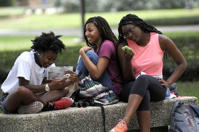 Students sit on a shaded bench in the Quad while waiting for their next class.
