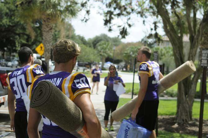 LSU freshman placekicker Kyle Pfau (30), junior linebacker Christian Pittman (50) and junior punter Jamie Keehn (38) assist students move into their dorms Wednseday August 20, 2014 outside West Hall.