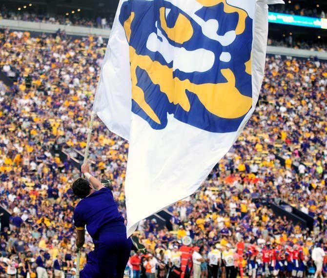 An LSU cheerleader runs with the flag down across the endzone to celebrate a touchdown Saturday, September 6, 2014 after the Tigers' 56-0 win against Sam Houston State in Tiger Stadium.