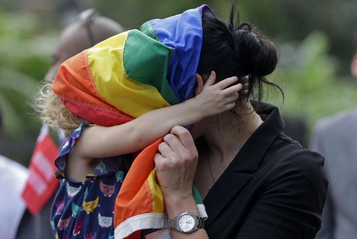 Ariel David, of New Orleans, who is gay, plays with a pride flag wide with her biological daughter Nelly David, 2, during a rally held in reaction to today's decision by a federal judge, which upheld Louisiana's ban on same-sex marriages, in New Orleans, Wednesday, Sept. 3, 2014. David who served in the U.S. Navy for six years and was deployed to the Middle East multiple times in support of the war on terror, said she attended because she and her partner cannot legally marry in the state. The rally was organized by Forum For Equality Louisiana. (AP Photo/Gerald Herbert)