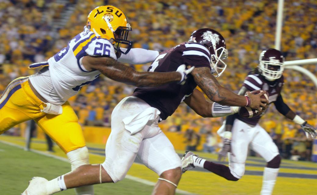 LSU senior safety Ronald Martin (26) from White Castle, La. attempts to tackle Mississippi State sophomore quarterback Dak Prescott (15) during the game Saturday September 20, 2014 where LSU lost 34-29 in Tiger Stadium.