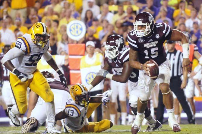 Mississippi State quaterback Dak Prescott (15) rushes the field while LSU senior defensive end Jermauria Rasco (59) tries to tackle him during the Mississippi State game Saturday September 20, 2014 where LSU lost 34-29 in Tiger Stadium.