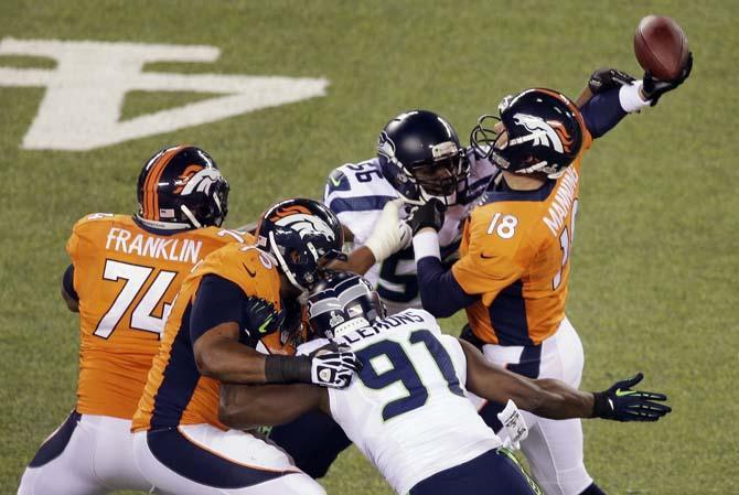 Denver Broncos' Peyton Manning is hit by Seattle Seahawks' Cliff Avril (56) during the first half of the NFL Super Bowl XLVIII football game Sunday, Feb. 2, 2014, in East Rutherford, N.J. Manning was charged with an interception on the play. (AP Photo/Charlie Riedel)