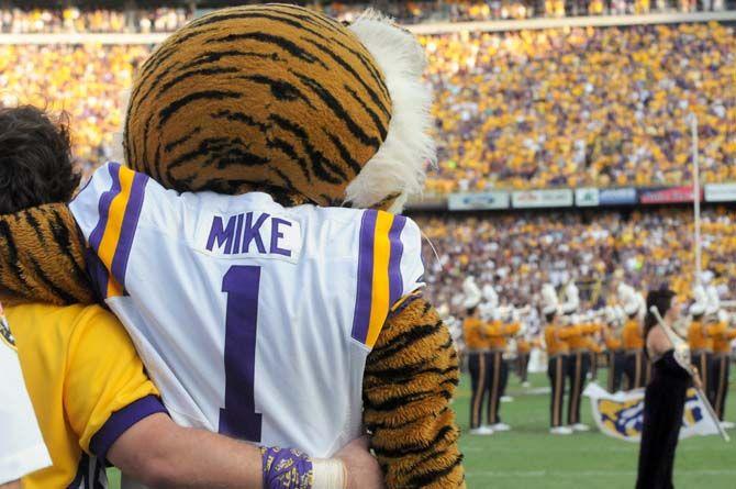 LSU's mascot Mike the Tiger stands in arms with a member of the LSU cheerleading squad to watch the Golden Band in Tiger Stadium Saturday, September 20, 2014 before a game against Mississippi State.