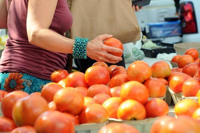 Customer picks through a table of fresh tomatoes at Red Stick Farmer's Market.