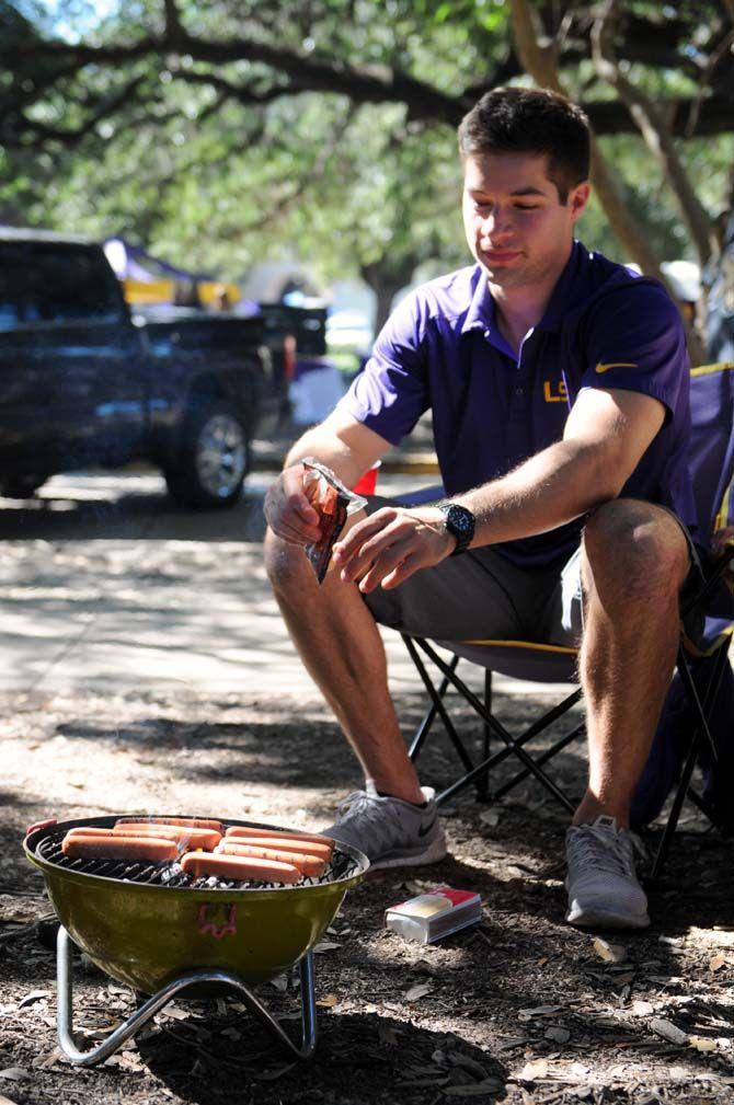 A fan cooks hotdogs over an open fire on the Parade Grounds during tailgate Saturday, October 25, 2014.