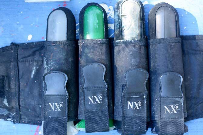 A belt of paintball canisters sit on a table before a game.