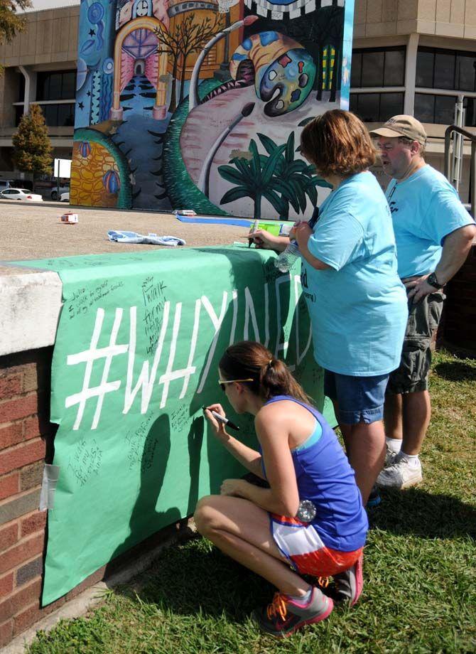 Participants sign a banner at the National Eating Disorder Association (NEDA) walk at the Riverfront Plaza on October 11, 2014.