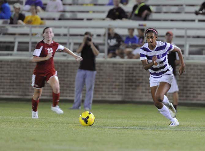 LSU sophomore forward Summer Clarke (4) runs past oponent senior defender Amber Moore (23) during the Tigers' 3-0 victory against Nicholls Tuesday, September 2, 2014 in LSU Soccer Stadium.