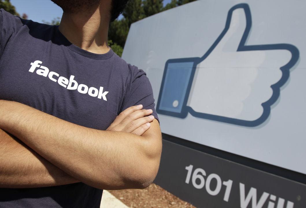 FILE - In this Aug. 17, 2012 file photo, a Facebook worker waits for friends to arrive outside of Facebook headquarters in Menlo Park, Calif. Facebook and Apple, long known for cushy perks such as free meals, laundry service and massages, are among some of Silicon Valley's biggest companies now eyeing reproductive expenses as the next batch of benefits to offer to their employees. (AP Photo/Paul Sakuma, File)