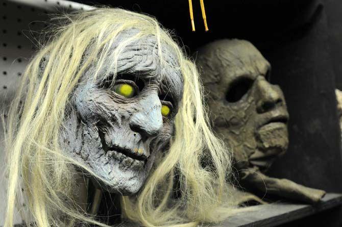 Masks sit on shelves in the costume room backstage at the 13th Gate.