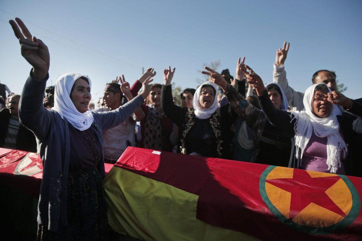 Kurdish mourners flash the V-sign as the chant slogans in front of coffins, during the funeral of Kurdish fighters Hanim Dabaan, 20, Idris Ahmad, 30, and Mohammed Mustafa, 25, killed in the fighting with the militants of the Islamic State group in Kobani, Syria, at a cemetery in Suruc, on the Turkey-Syria border, Tuesday, Oct. 21, 2014. The three fighters_ two men and a young woman barely out of her teens _ were killed during the last few days battling Islamic State fighters in the Kurdish Syrian town of Kobani, also known as Ayn Arab, located on the border with Turkey. They were buried without their families present; in the chaos of war, since mid-September, hundreds of thousands of Kurds have become refugees, and contacting the families of those killed is not always possible. It wasn&#8217;t immediately clear if the families of the fighters even knew their loved ones were dead. (AP Photo/Lefteris Pitarakis)