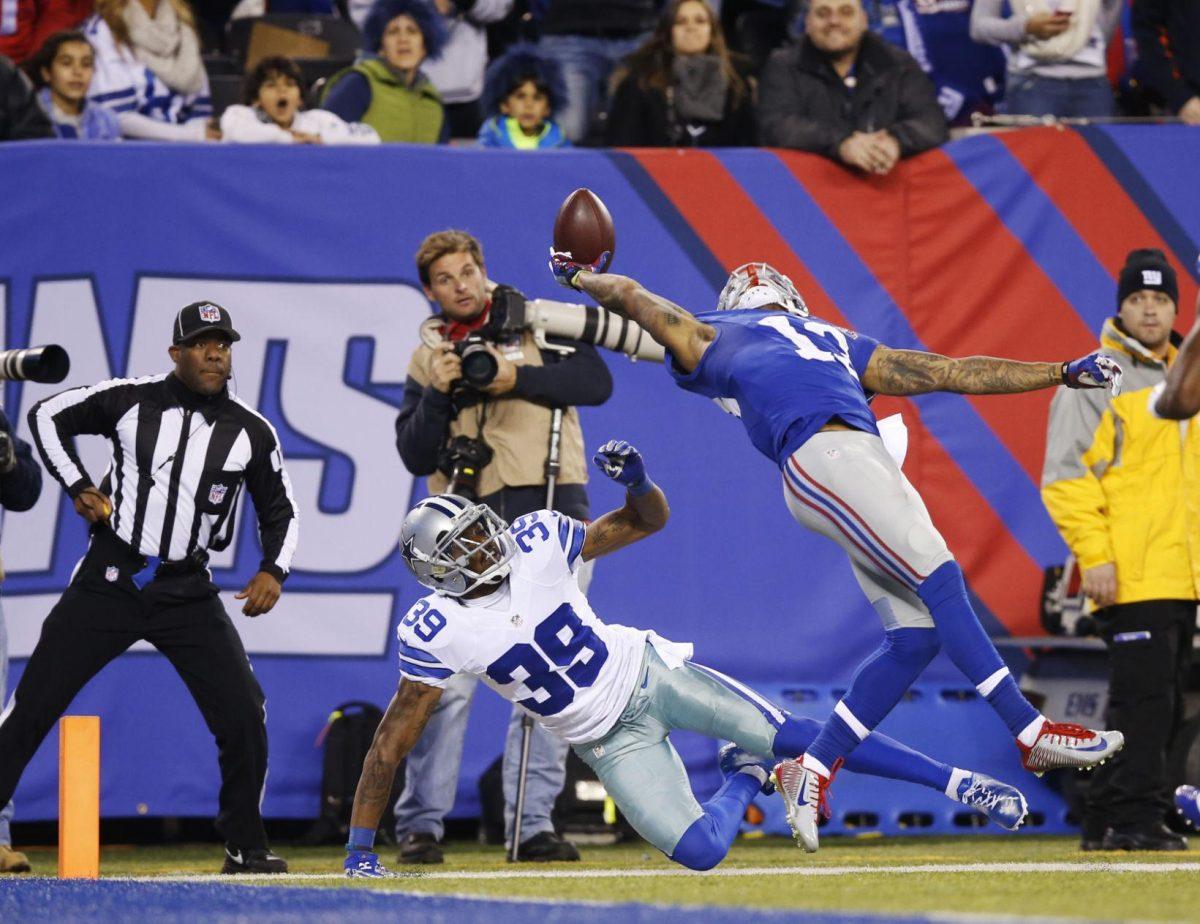 FILE - In this Nov. 23, 2014, file photo, New York Giants wide receiver Odell Beckham Jr. (13) makes a one-handed catch for a touchdown against Dallas Cowboys cornerback Brandon Carr (39) in the second quarter of an NFL football game in East Rutherford, N.J. The one-handed catch by Odell Beckham Jr. that became the most talked-about play from Sunday did more than just boost his standing with the New York Giants, it paid off a routine growing popular among many skill players of practicing the impractical, one-handed circus grab. (AP Photo/Kathy Willens, File)