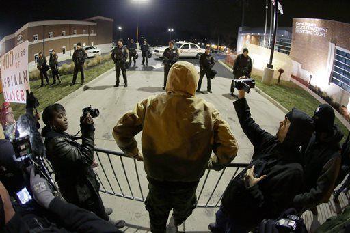 A protester confronts police in front of the Ferguson Police department before the announcement of the grand jury decision about whether to indict a Ferguson police officer in the shooting death of Michael Brown, Monday, Nov. 24, 2014, in Ferguson, Mo. A Missouri grand jury heard evidence for months as it weighed whether to indict Ferguson police Officer Darren Wilson in the Aug. 9 fatal shooting of Brown. (AP Photo/Charlie Riedel)