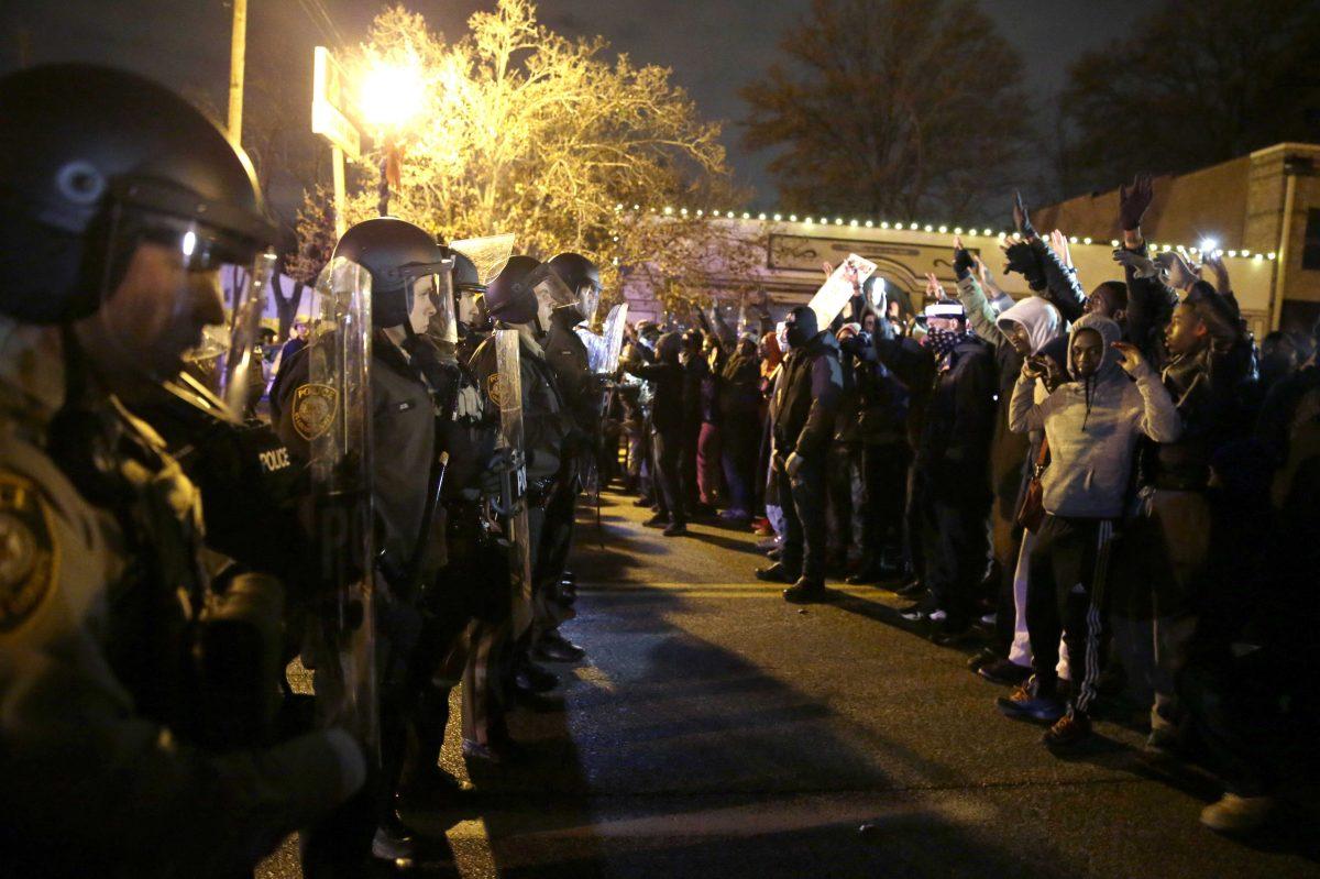 Police officers stand guard as protesters react to the announcement of the grand jury decision not to indict police officer Darren Wilson in the fatal shooting of Michael Brown, an unarmed black 18-year-old, Monday, Nov. 24, 2014, in Ferguson, Mo. (AP Photo/David Goldman)