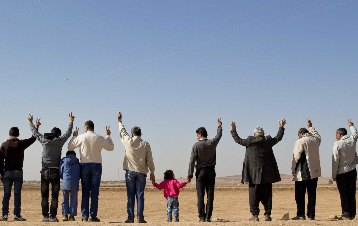 Kurds stand in line and flash victory signs during a solidarity rally with the Syrian city of Kobani in the village of Caykara, Turkey, on the Turkey-Syria border, just across from Kobani, Tuesday Nov. 11, 2014. Kurds rally daily in villages in Turkey on the border with Syria in solidarity with the embattled Syrian city of Kobani, which has been under a brutal siege by the Islamic State group. (AP Photo/Vadim Ghirda)