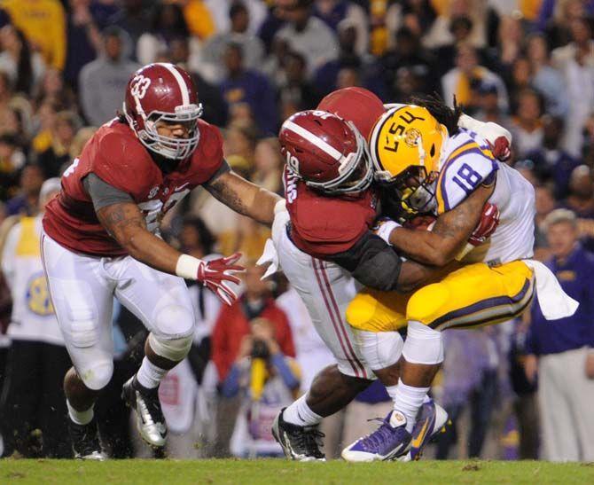 Alabama junior linebacker Reggie Ragland (19) and senior linebacker Trey DePriest (33) run towards and tackle LSU senior running back Terrence Magee (18) Saturday, November 8, 2014 during the Tigers' 20-13 loss against the Crimson Tide in Tiger Stadium.