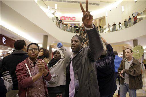 Protest organizer Derrick Robinson flashes a peace sign as he leads a group inside Chesterfield Mall Friday, Nov. 28, 2014, in Chesterfield, Mo. The crowd disrupted holiday shopping at several locations on Friday amid a protest triggered by a grand jury's decision not to indict the police officer who fatally shot Michael Brown in nearby Ferguson. (AP Photo/Jeff Roberson)