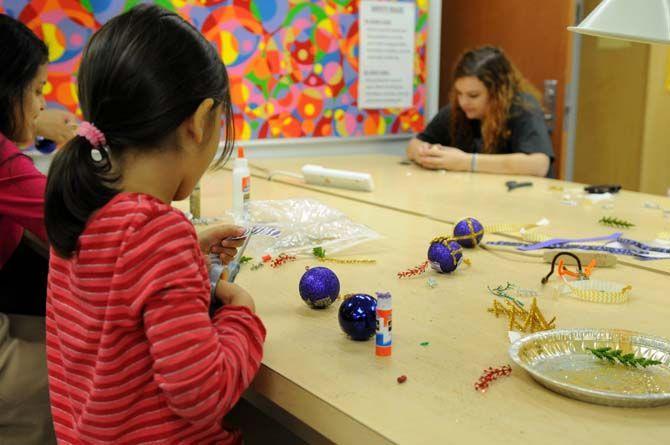 A young girl cuts a piece of tiger-striped ribbon for her ornament in the Leisure Arts studio in the Union Friday, Dec. 5, 2014 for "Deck the Union Halls."