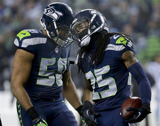 Seattle Seahawks cornerback Richard Sherman, right, celebrates after intercepting a pass by Carolina Panthers quarterback Cam Newton with outside linebacker K.J. Wright (50) during the first half of an NFL divisional playoff football game in Seattle, Saturday, Jan. 10, 2015. (AP Photo/Elaine Thompson)