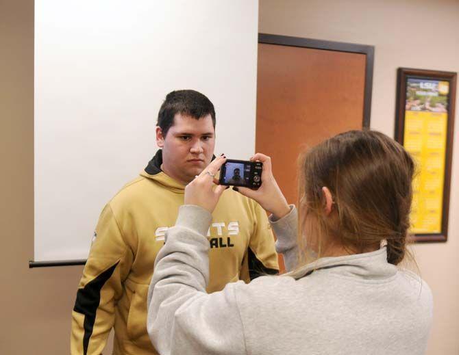 Junior finance major Daniel Huemann poses on Thursday, Jan. 15, 2015, for a picture taken by Tigercard office worker and student Jennifer Preau in front of the new passport station.