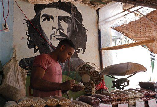 A worker who sells beans counts money at a state-run market stall decorated with a mural of Cuban revolutionary hero Ernesto "Che" Guevara in Havana, Cuba, Saturday, Dec. 20, 2014. After the surprise announcement on Wednesday of the restoration of diplomatic ties between Cuba and the U.S., many Cubans expressed hope that it will mean greater access to jobs and the comforts taken for granted elsewhere, and lift their struggling economy. However others feared a cultural onslaught, or that crime and drugs, both rare in Cuba, will become common along with visitors from the U.S. (AP Photo/Desmond Boylan)