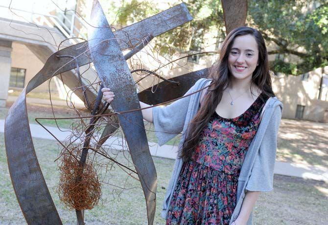 LSU sculpture major Suzannah Burke poses Saturday, Jan. 17, with her latest creation. The sculpture titled "A Personal Narrative" is on display in the Sculpture Garden by the Studio Arts building.