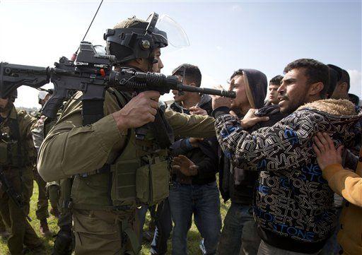 An Israeli soldier grabs a Palestinian during a march by landowners and activists attempting to plant olive tree saplings near the Israeli settlement Ofra, outside the Palestinian town of Silwad, near the west bank city of Ramallah, Monday, Feb. 9, 2015. (AP Photo/Majdi Mohammed)