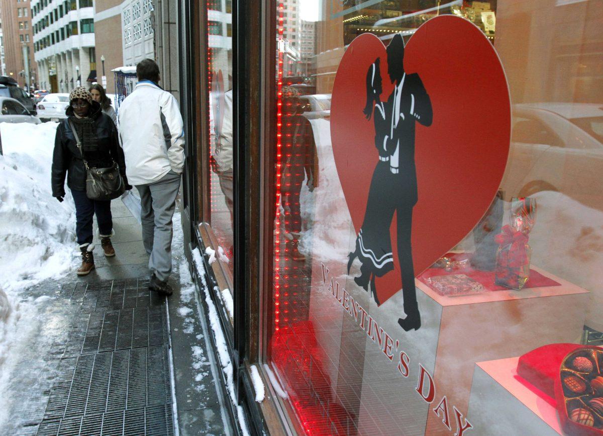 Commuters walk past piles of snow in front of Au Chocolat, Wednesday, Feb. 11, 2015, in downtown Boston. With streets boxed in by mountains of snow, delivery drivers in the region are struggling to deliver daily supplies to downtown stores, as well as Valentine's Day flowers and edibles. (AP Photo/Bill Sikes)