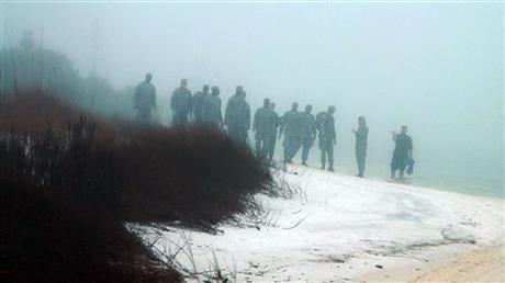 Military personnel wade in the water and search on the beach under heavy fog at Eglin Air Force Base, Fla., Wednesday, March 11, 2015, for the wreckage of a military helicopter that crashed with 11 service members aboard. The helicopter went down Tuesday evening. A Pentagon official says all aboard are presumed dead. (AP Photo/Melissa Nelson-Gabriel)