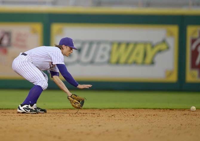 LSU senior outfielder Jared Foster (17) bends down to retrieve a ground ball in between innings on Wednesday, April 15, 2015, during the Tigers' 11-2 win against Lamar in Alex Box Stadium.